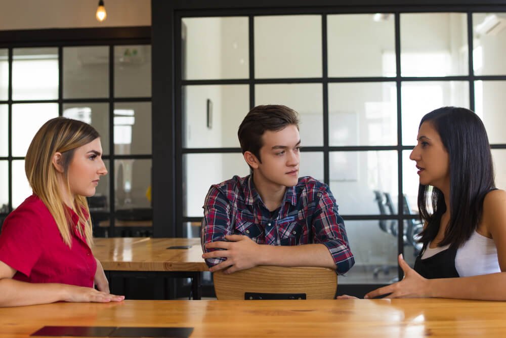 Three professionals discussing strategy in a collaborative office meeting