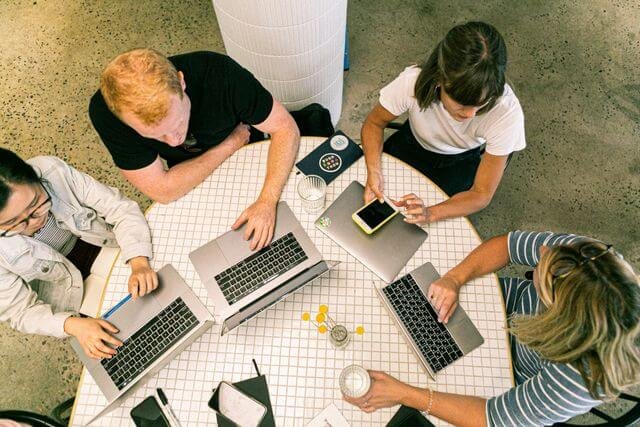 Overhead view of a diverse team collaborating with laptops around a table